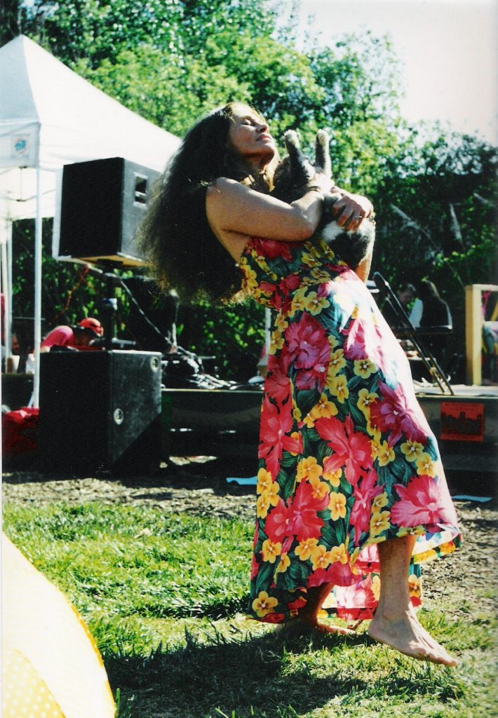 Dancer with cat in arms in the sunshine at a People's Park event